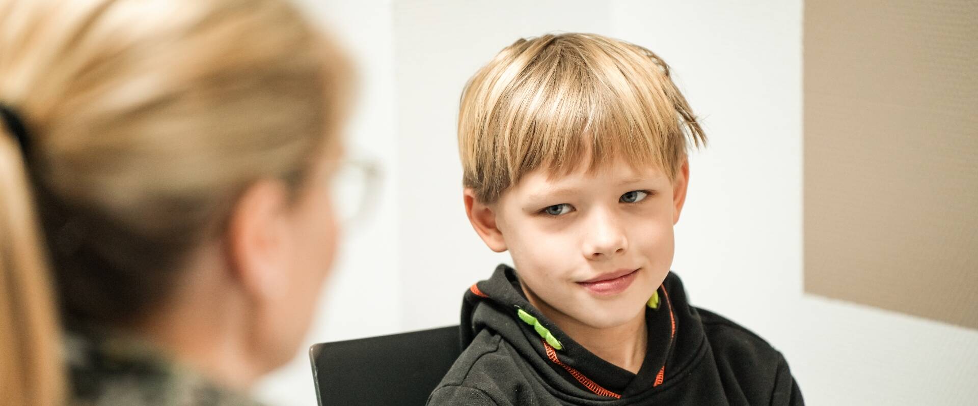 Kleiner Junge wird von einer Mitarbeiterin befragt
