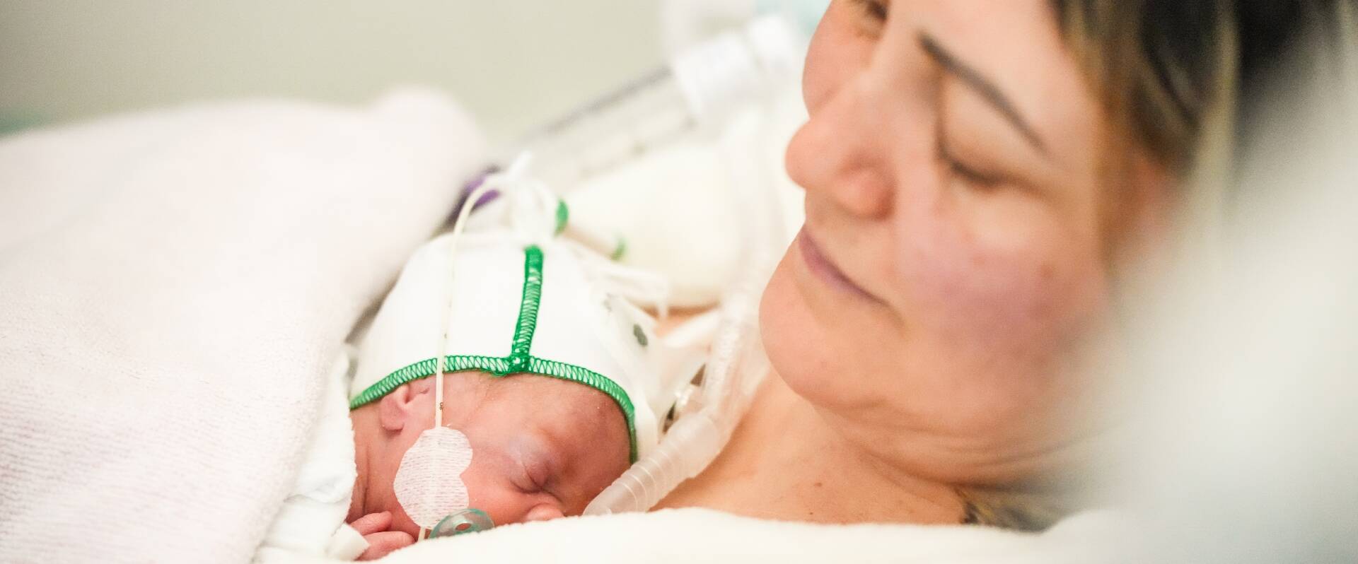 Mutter mit Frühchen auf ihrer Brust liegend